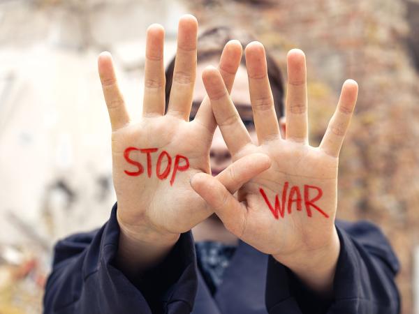 Woman's hands raised with slogan written in red Stop War